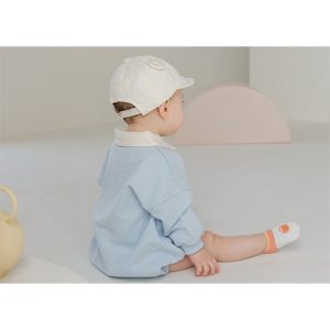 A baby in a light blue Gid coverall with a white and beige hat and matching socks, looking comfortable and stylish