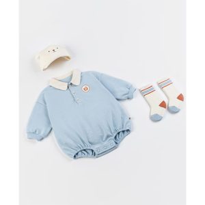 A baby in a light blue Gid coverall with a white and beige hat and matching socks, looking comfortable and stylish