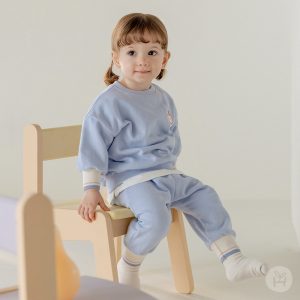 Adorable toddler in blue Onbie Baby Set-Up with apple embroidery, available at Tiny You Baby Store.