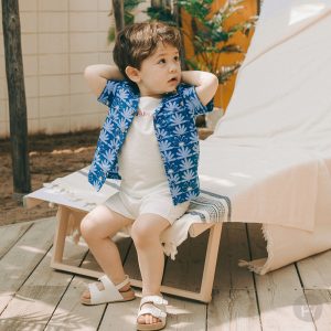 Showcasing the Spica Baby Set-Up with its tropical blue patterns, positioned against a serene beach backdrop. Ideal for fashionable summer days