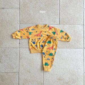 Kids' Jurassic Top and Bottom Sets displayed on a stone floor, featuring bright dinosaur and vehicle prints in yellow and white